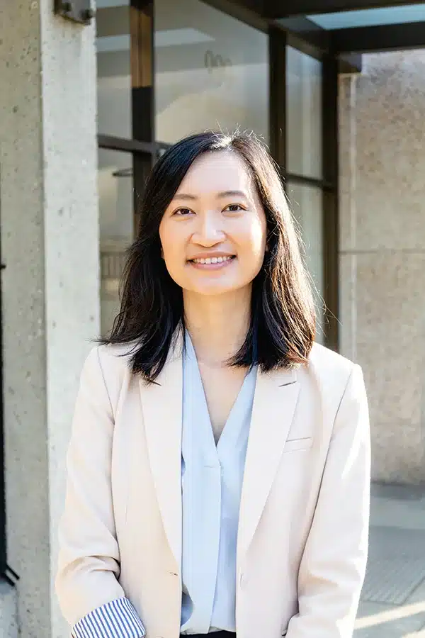 Team Portrait of Jenny Vo, standing in a white business suit in front of an office building.