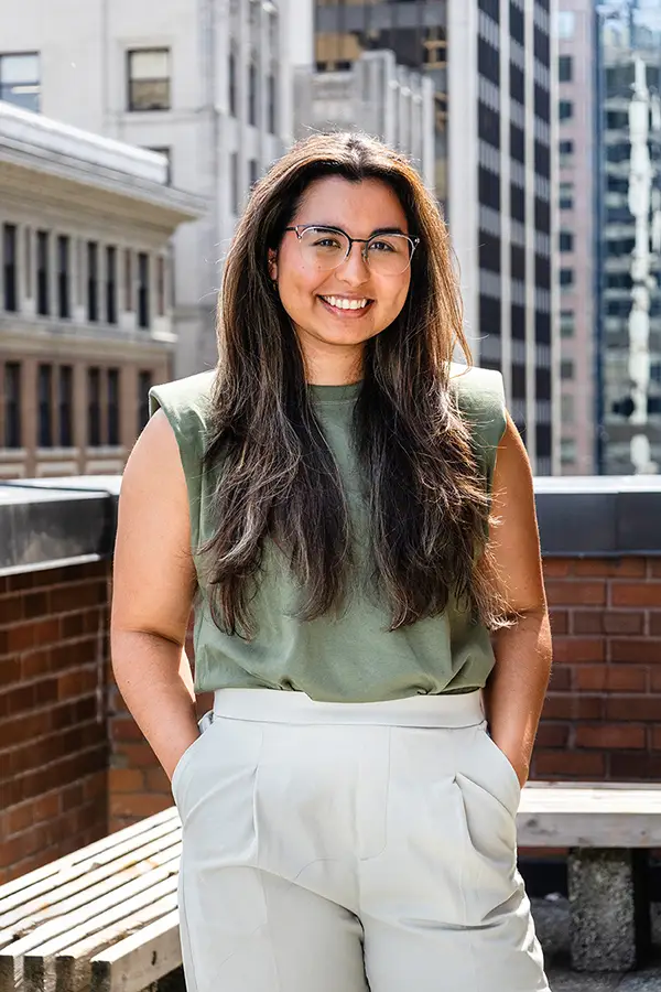 Team Portrait of Monica Cordoba, Program Coordinator at The Coaching Studio, standing in front of the Vancouver Skyline