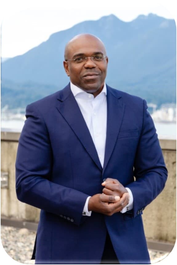 Team Portrait of Okenge Yuma Morisho, Leadership Consultant r at The Coaching Studio, standing in front of the Vancouver Skyline